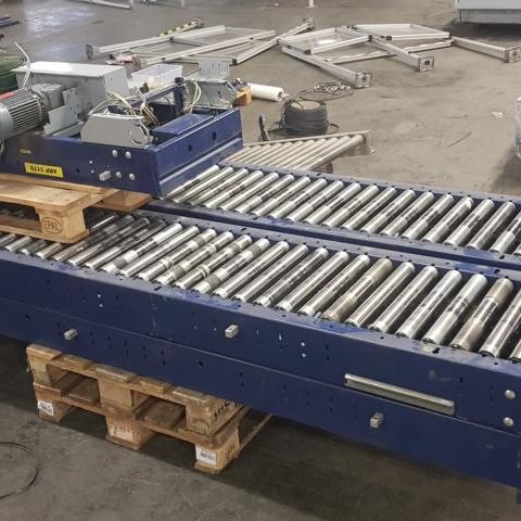 Förderband mit Rollen auf Holzpaletten in einer Lagerhalle.