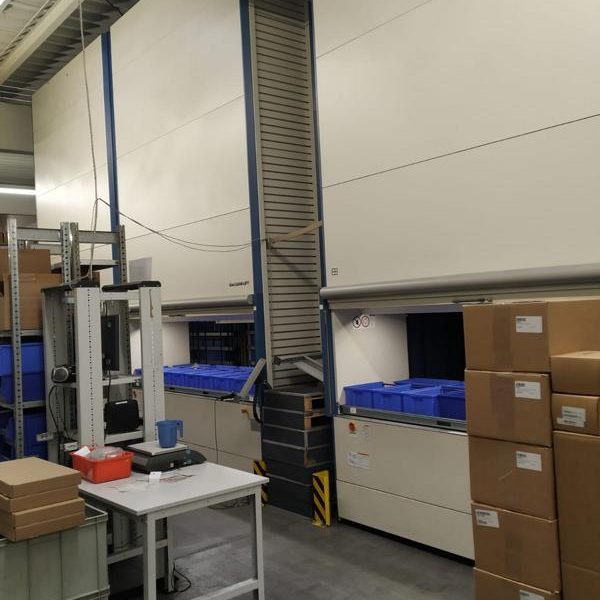 Lagerraum mit automatisierten Regalsystemen und blauen Transportboxen.