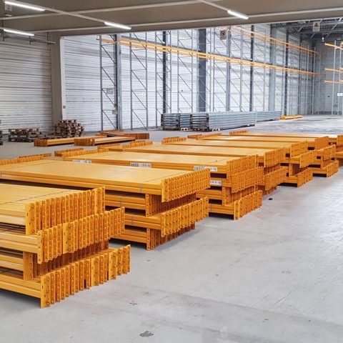 Gelbe Metallregale gestapelt in einem großen, offenen Lagerraum.