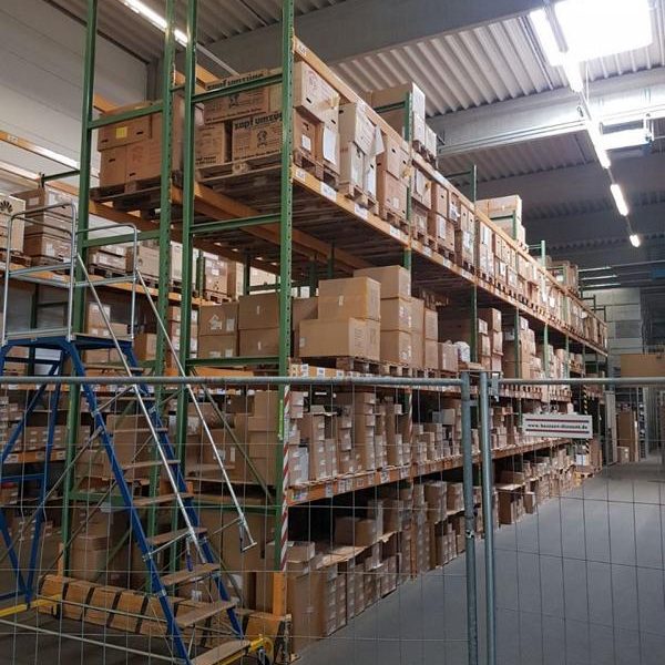 Lager mit hohen Regalen, voller Kartons und einem Gerüst auf der Vorderseite.