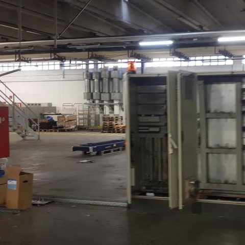 Leerer Lagerraum mit Regalen, Kisten und einer offenen Tür.