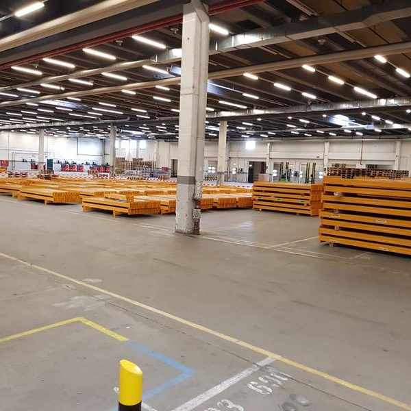 Großer Lagerraum mit mehreren gestapelten orangefarbenen Paletten.