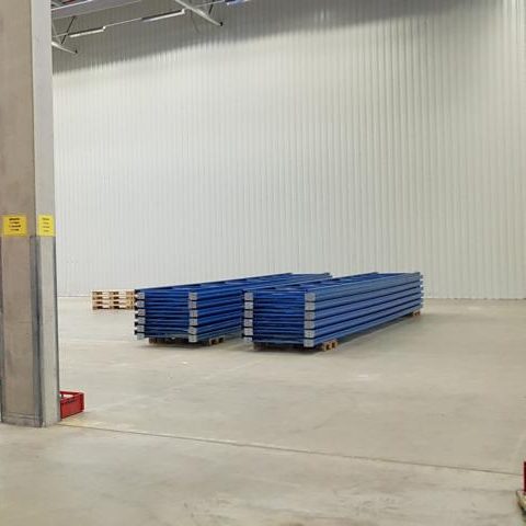 Blaue Paletten gestapelt in einem leeren Lagerraum.
