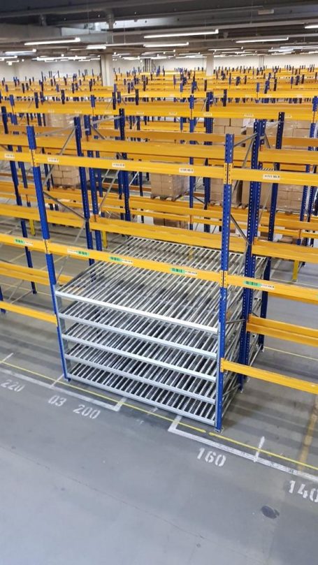 Leere Lagerregale mit blauen und gelben Strukturen in einem großen Raum.